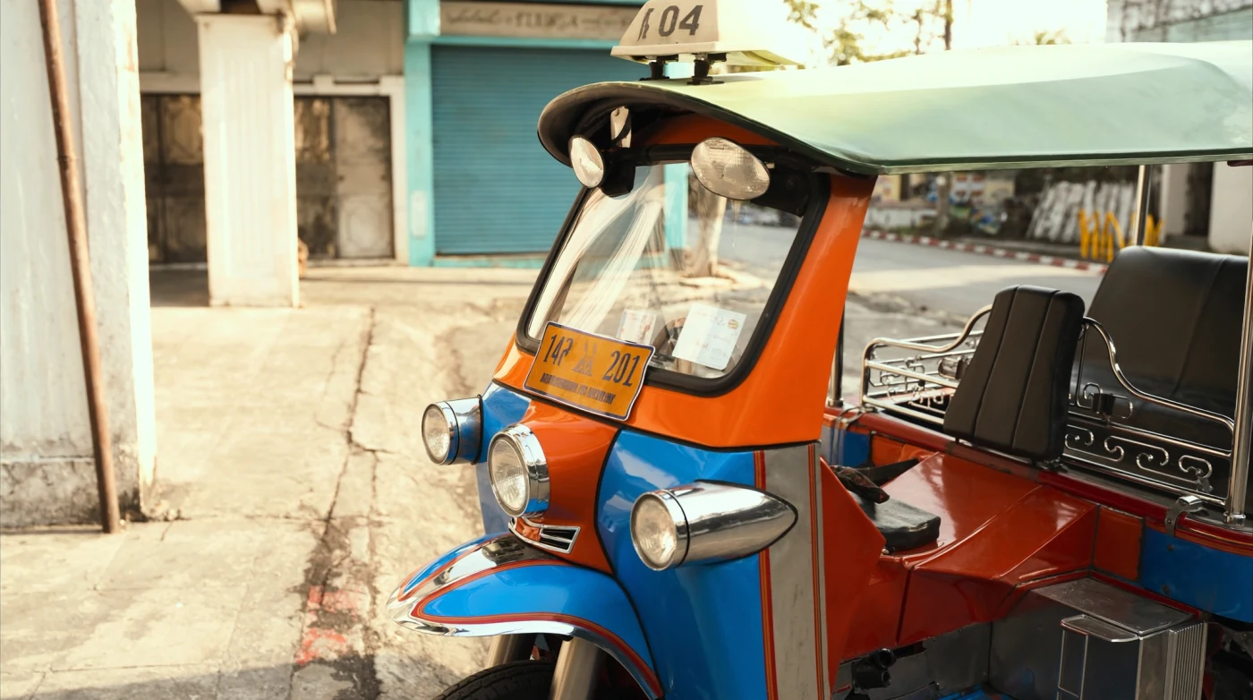 Brightly painted tuk-tuk parked on a Bangkok street in afternoon light