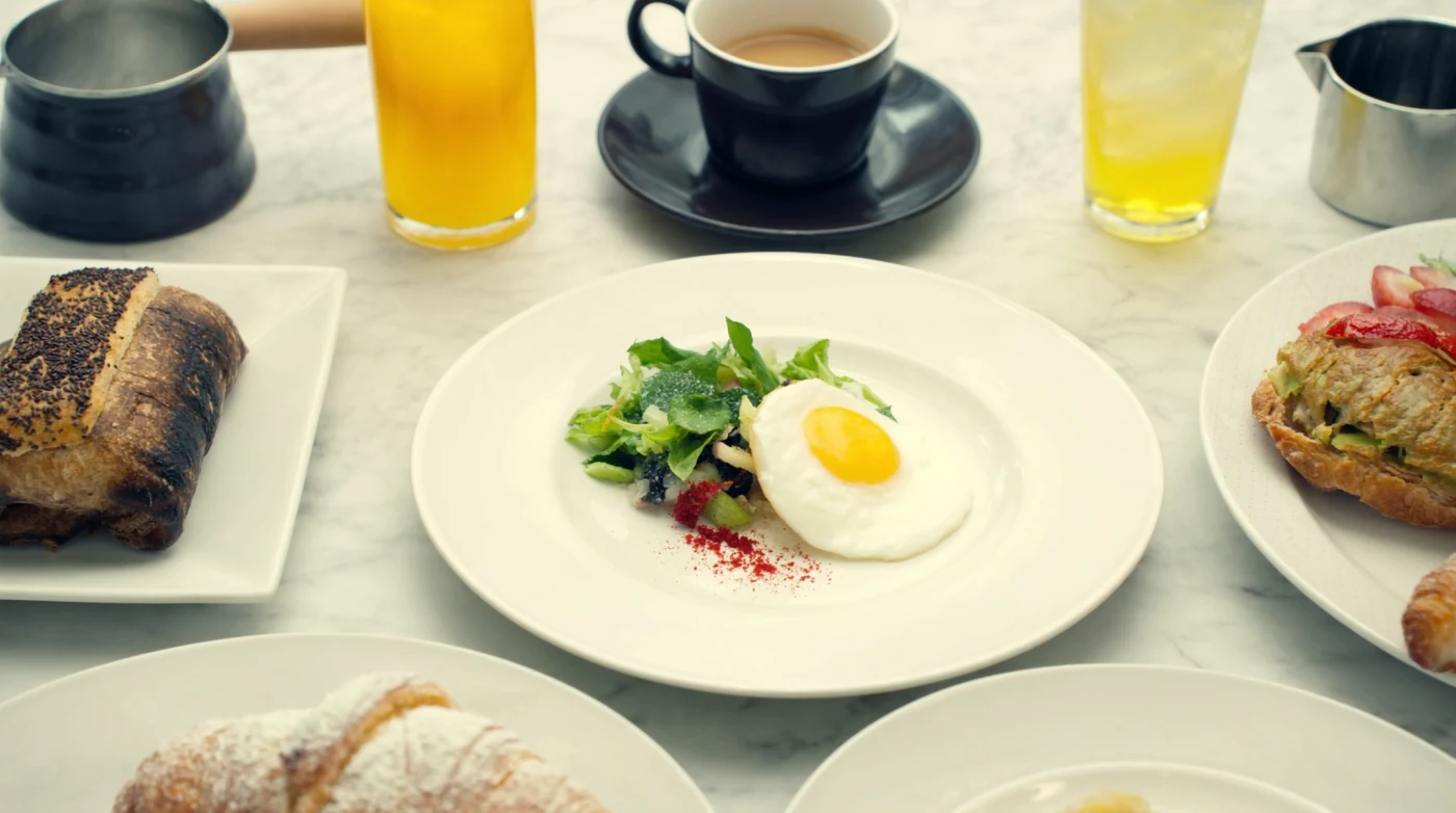 Brunch table with coffee, pastries and plates in a bright Bangkok cafe