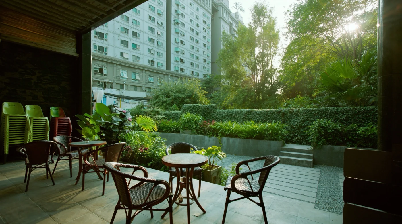Shaded outdoor cafe terrace in Bangkok with wooden tables and greenery