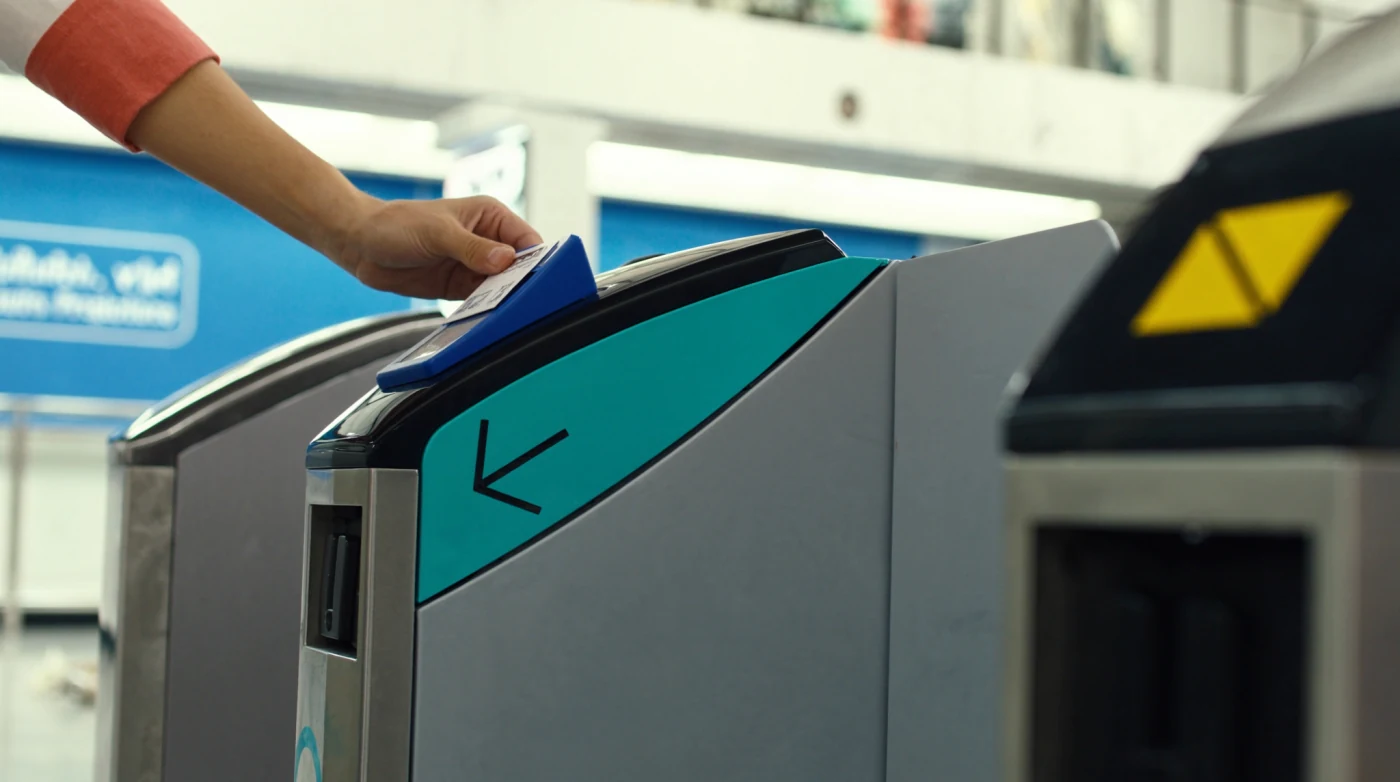Stored value card being tapped on a ticket gate reader in a Bangkok train station