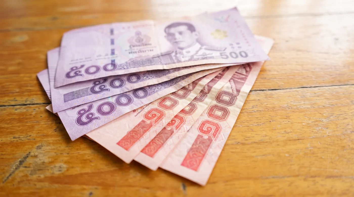 Thai baht banknotes fanned out on a wooden surface