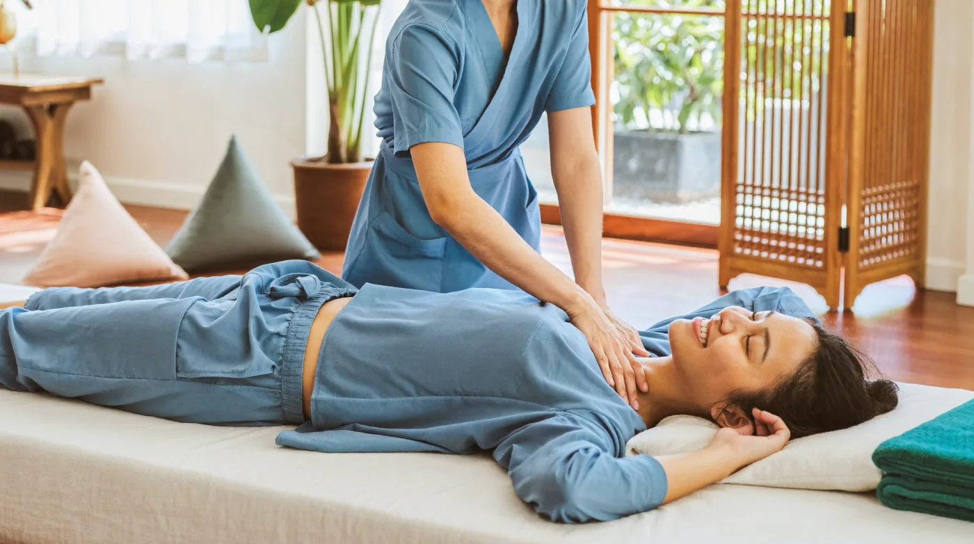 Therapist working a relaxed customer’s shoulders in a traditional Thai massage shop