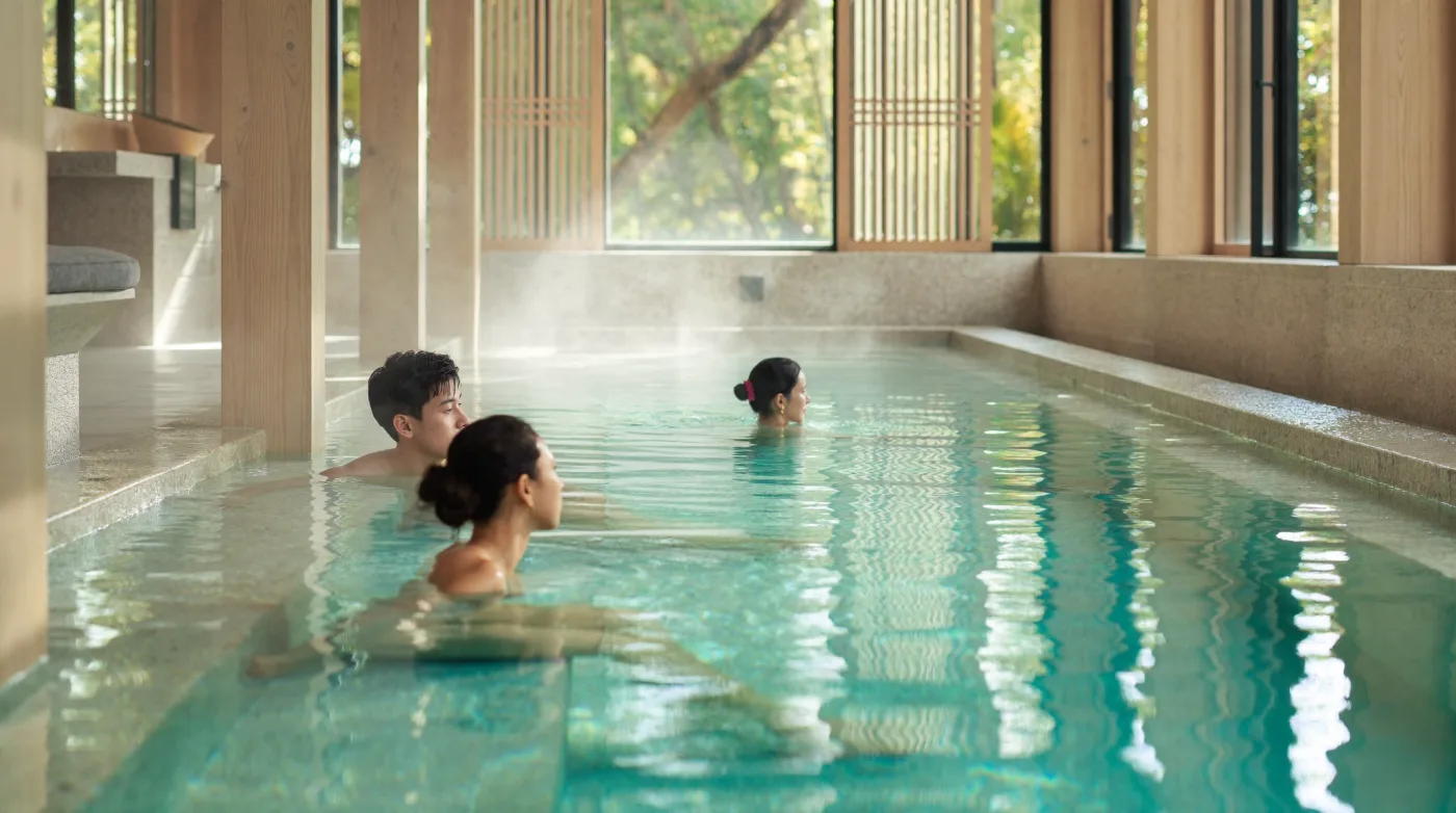 Couple relaxing in a steaming stone mineral pool at a Japanese-style bathhouse in Bangkok