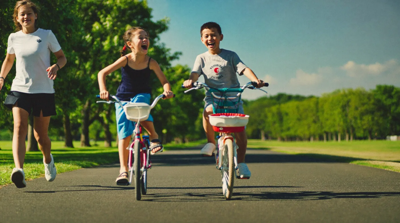 Children cycling along a sunlit park path in northern Bangkok