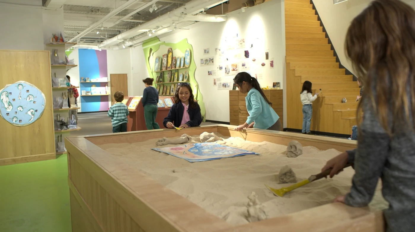 Fossil dig pit and hands-on exhibits in a children’s discovery museum