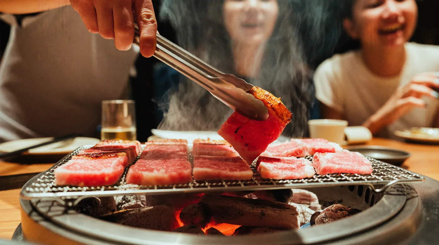 Sliced wagyu beef on a charcoal grill at a Japanese yakiniku restaurant