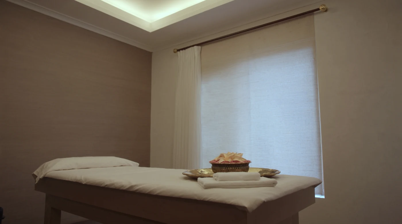 Calm treatment room with a massage bed, folded towels and soft lamp light